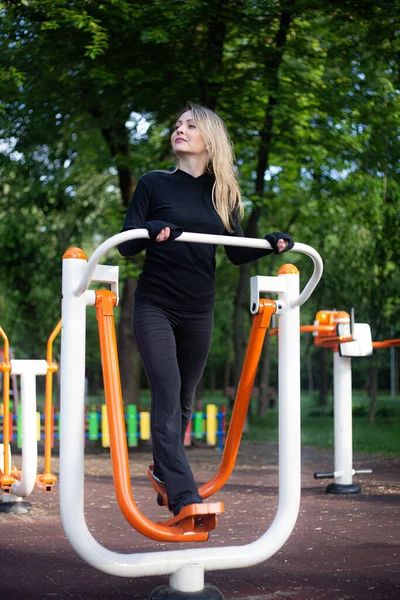 The girl on the summer sports ground does sports exercises on the stepper. Healthy lifestyle.