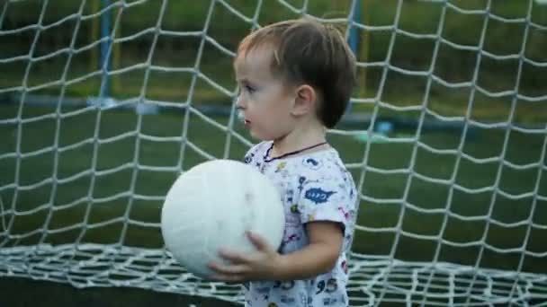 Мальчик держит мяч в руках на футбольном поле. — стоковое видео