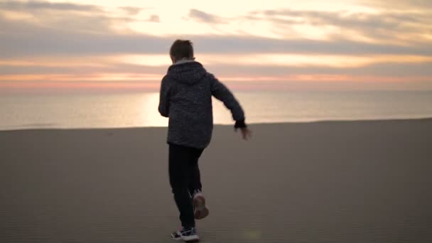 Chlapec, běh po pláži při západu slunce. — Stock video