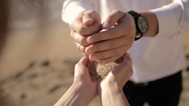 De man giet zand in handen van de dames — Stockvideo