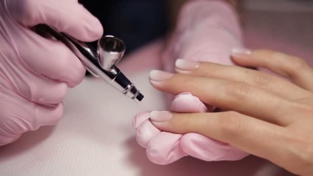 Master makes manicure with airbrush in white — Stock Video