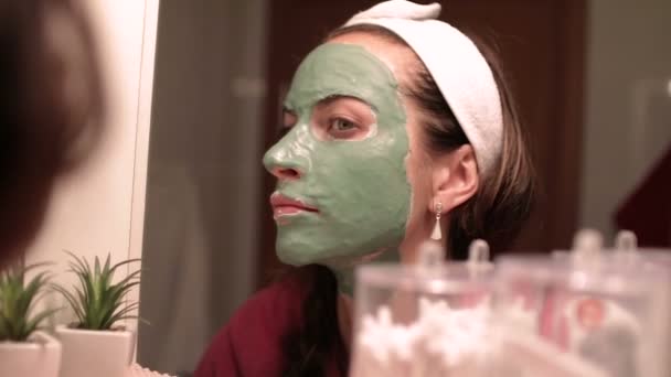 Krásná žena s obličejové masky. Lázeňská léčba pro mladá žena přijímat obličejové masky. — Stock video