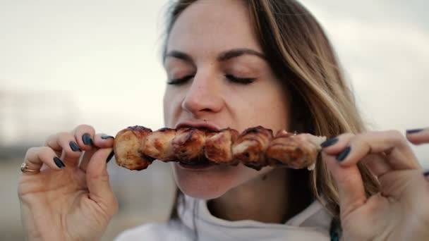 Schöne Frau beißt riesige Fleischstücke essen mit wütenden Händen unangemessen in Großaufnahme — Stockvideo