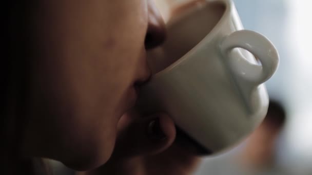 Young beautiful girl in a hat with a cup of coffee in hand and drinking it. — Stock Video