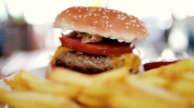 Büyük bir pirzola ve patates kızartması ketçap ile bir kavanoz ile lezzetli hamburger. Yakın çekim 60fps