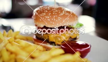 Büyük bir pirzola ve patates kızartması ketçap ile bir kavanoz ile lezzetli hamburger. Yakın çekim 60fps