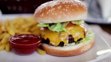 Büyük bir pirzola ve patates kızartması ketçap ile bir kavanoz ile lezzetli hamburger. Yakın çekim 60fps