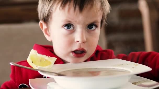 Kleine jongen eet soep en brood aan tafel — Stockvideo