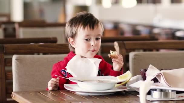 Menino come sopa e pão na mesa — Vídeo de Stock