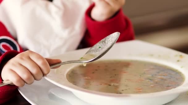 Kleine jongen eet soep en brood aan tafel — Stockvideo