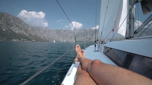 Człowiek na jachcie żaglowych leży na pokładzie i dostaje przyjemność wiatr wieje w żagle — Wideo stockowe