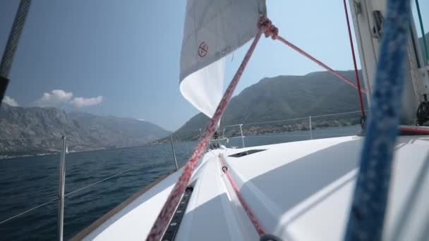 Die Segeljacht drehen, das Segel und die Bewegungsrichtung vor dem Hintergrund der wunderschönen Berge und des blauen Himmels ändern — Stockvideo