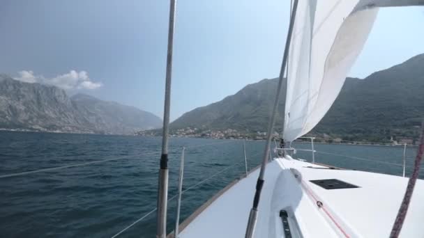 Vire o iate à vela, mudar a vela e a direção do movimento contra o pano de fundo de belas montanhas e céu azul — Vídeo de Stock