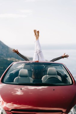 Mutlu kadın güzel manzaralı kırmızı üstü açık bir arabada oturuyor.