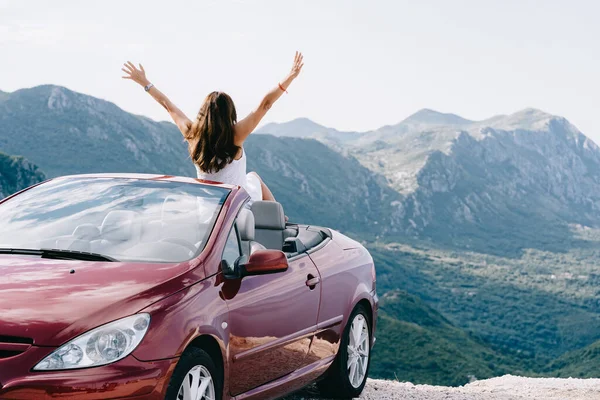 Mujer feliz se sienta en un coche convertible rojo con una hermosa vista Imagen De Stock