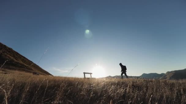 Muž na vrcholku hory sedí při západu slunce na lavičce — Stock video