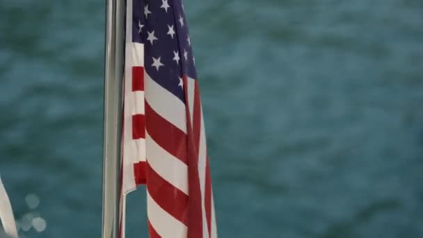 Bandera de EE.UU. evoluciona en el viento contra el agua — Vídeo de stock