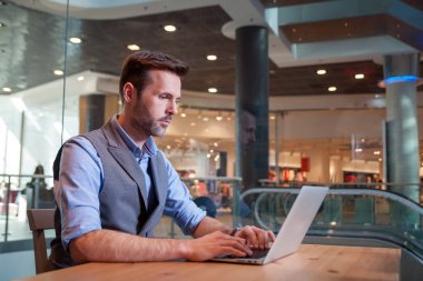 Kendine güvenen işadamı Cafe city Alışveriş merkezinde dizüstü bilgisayar üzerinde çalışan