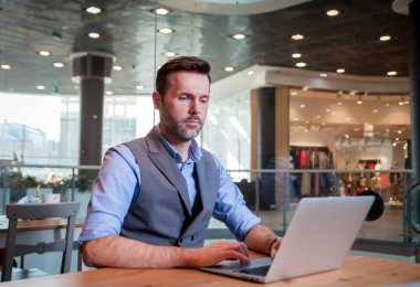 Kendine güvenen işadamı Cafe city Alışveriş merkezinde dizüstü bilgisayar üzerinde çalışan