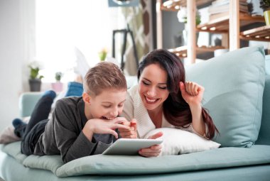 Anne ve oğlu koltukta yalan ve dijital tablet evde kullanma