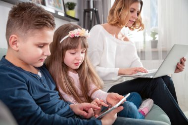 Genç Anne kullanarak dizüstü ve tablet bilgisayar ile oynayan çocuklar