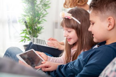 Genç Anne kullanarak dizüstü ve tablet bilgisayar ile oynayan çocuklar