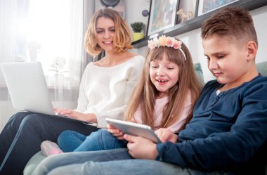 Genç Anne kullanarak dizüstü ve tablet bilgisayar ile oynayan çocuklar