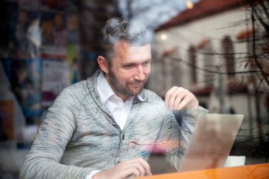 Kafede dizüstü bilgisayarda çalışan orta yaş erkeğin