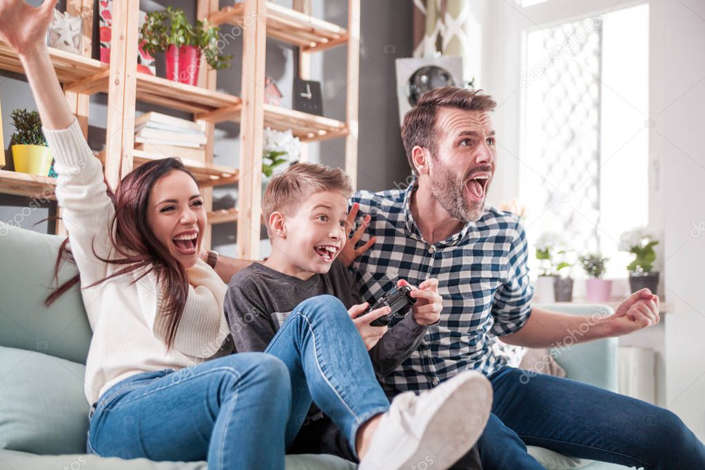 Excited family playing video game on console at home