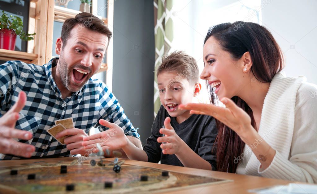 Happy family absorbedly playing board game at home