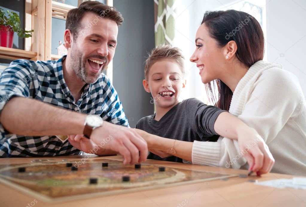 Happy family absorbedly playing board game at home