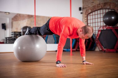 Spor salonunda egzersiz topu ile çalışan sportif adam