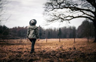 Büyük yaşlı ağacın yanında yürüyen genç kadın arkadan görünüm