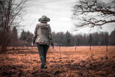 Büyük yaşlı ağacın yanında yürüyen genç kadın arkadan görünüm
