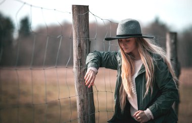 Genç kadın şık şapka kırsal çit poz