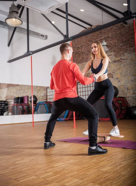 Νεαρός Άνδρας Βοηθά Γυναίκα Κάνει Άσκηση Ισορροπίας Στο Γυμναστήριο — Φωτογραφία Αρχείου