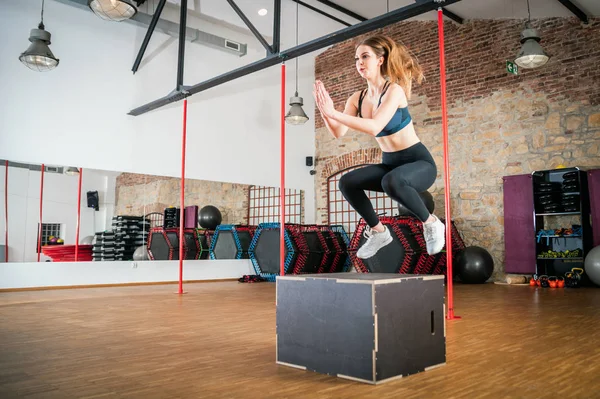 Sporty woman doing box jump exercise at fitness gym