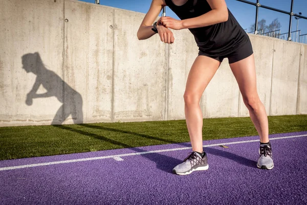 女子在体育场跑道上奔跑 设置健身智能手表 — 图库照片
