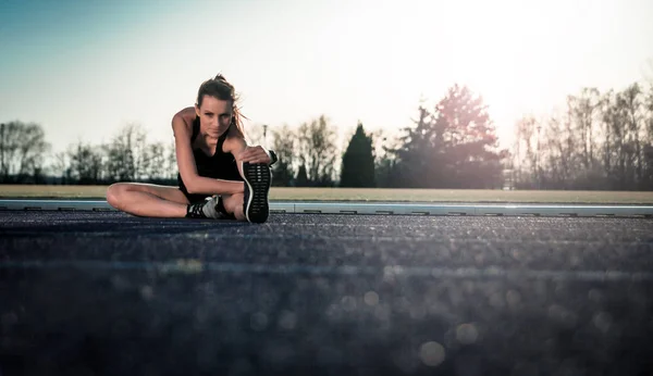 Mujer Atlética Joven Estirándose Pista Atletismo Del Estadio Atardecer — Foto de Stock