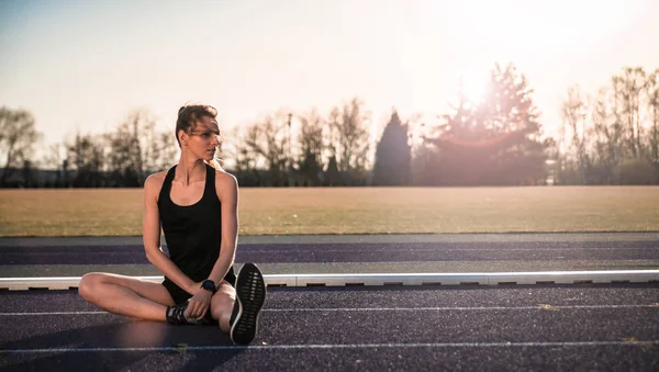 Junge Athletische Frau Dehnt Sich Bei Sonnenuntergang Auf Der Stadionlaufbahn — Stockfoto