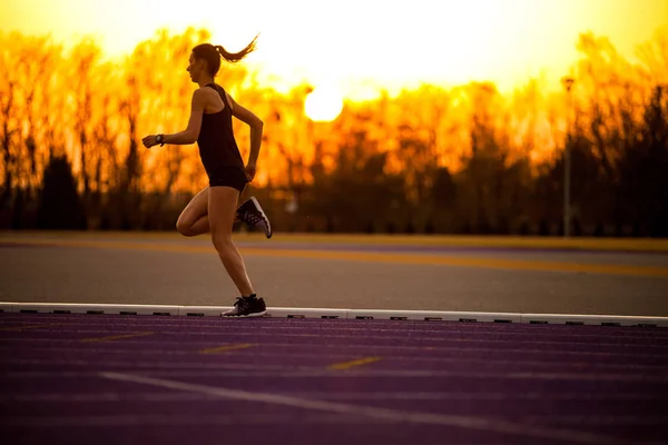 运动妇女在跑道赛跑在日落 — 图库照片