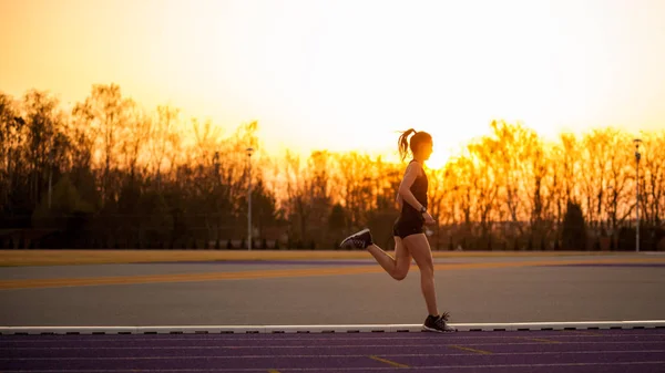 运动妇女在跑道赛跑在日落 — 图库照片