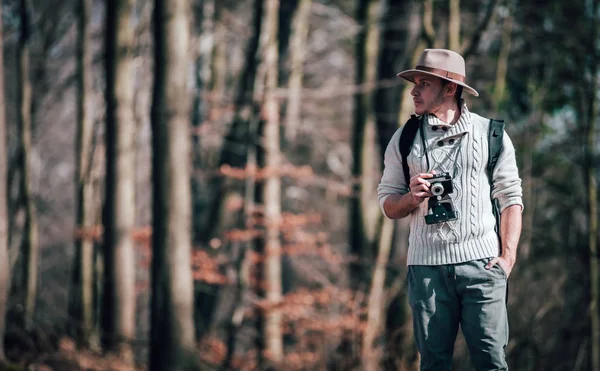 旅游男子与老式相机和背包漫步在秋季森林 — 图库照片