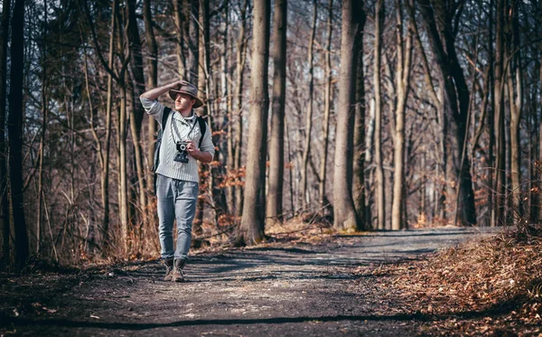 ビンテージ カメラとバックパックが秋の森を歩く旅行者男 — ストック写真