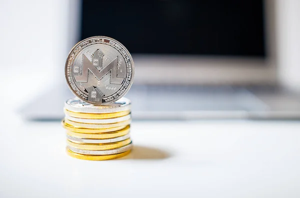 Monero coin and pile of coins with laptop computer on background