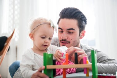 Baba ve kızı evde kanepe üzerinde oyuncaklar ile oynama