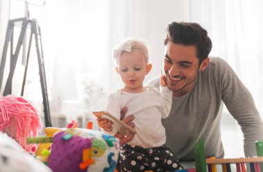Baba ve kızı evde kanepe üzerinde oyuncaklar ile oynama