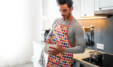 Genç adam evde modern mutfakta yiyecek hazırlama