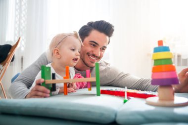 Baba ve kızı evde kanepe üzerinde oyuncaklar ile oynama