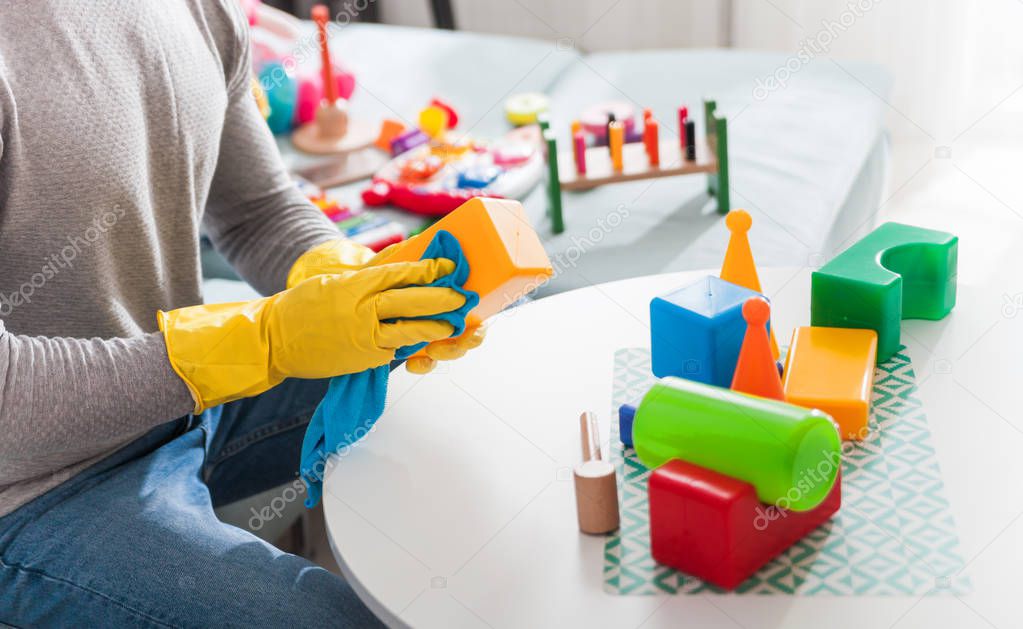 Young father cleaning toys and table after playing with child at home